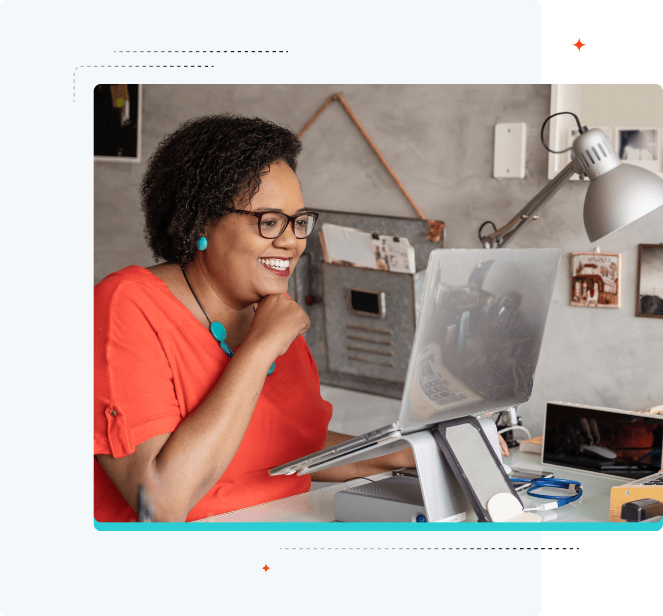 Image of a smiling women looking at her laptop which is on an elevated stand.