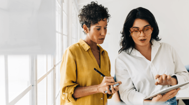 Image of two women at work viewing an ipad. 