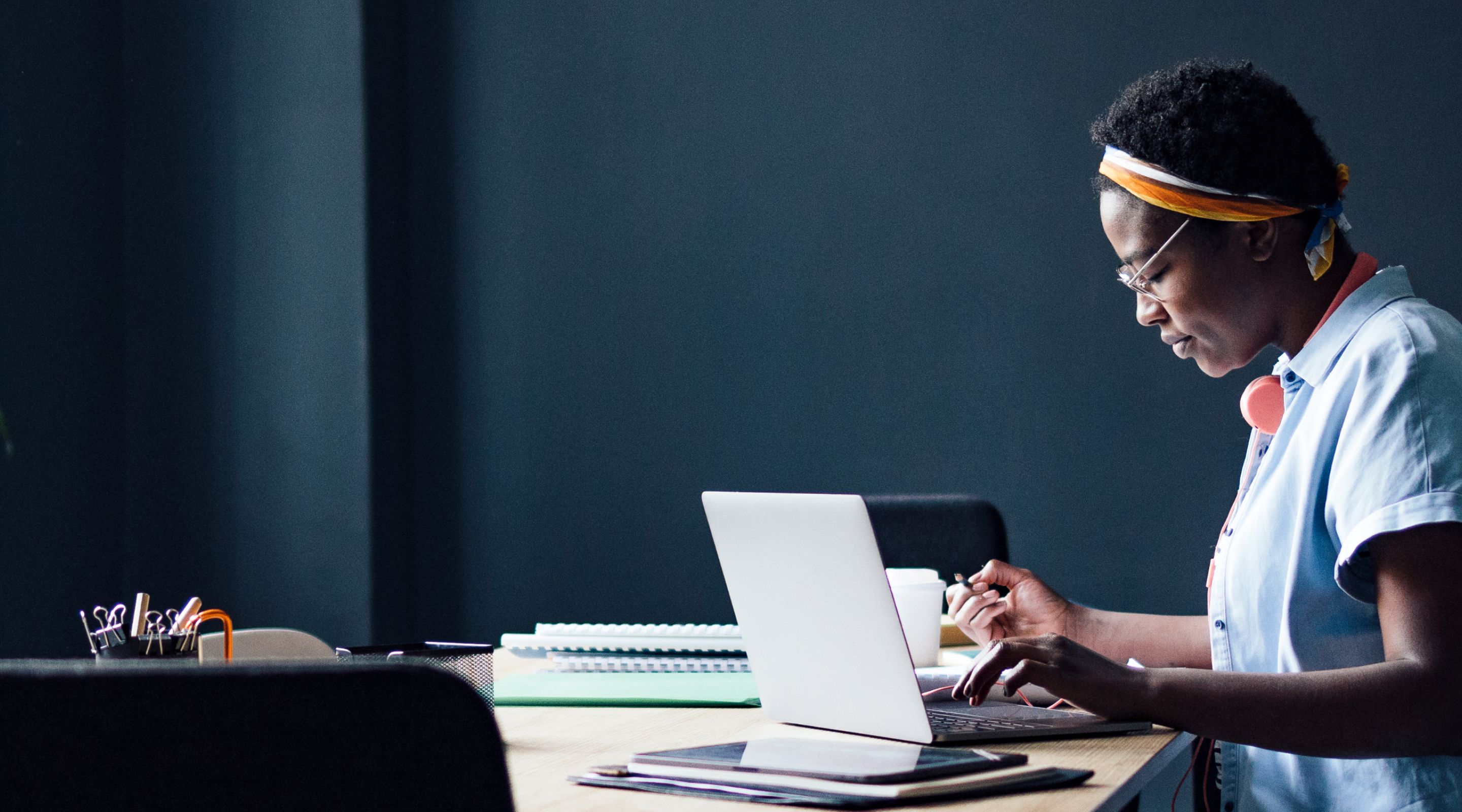 A woman is sitting at a desk using a laptop computer.