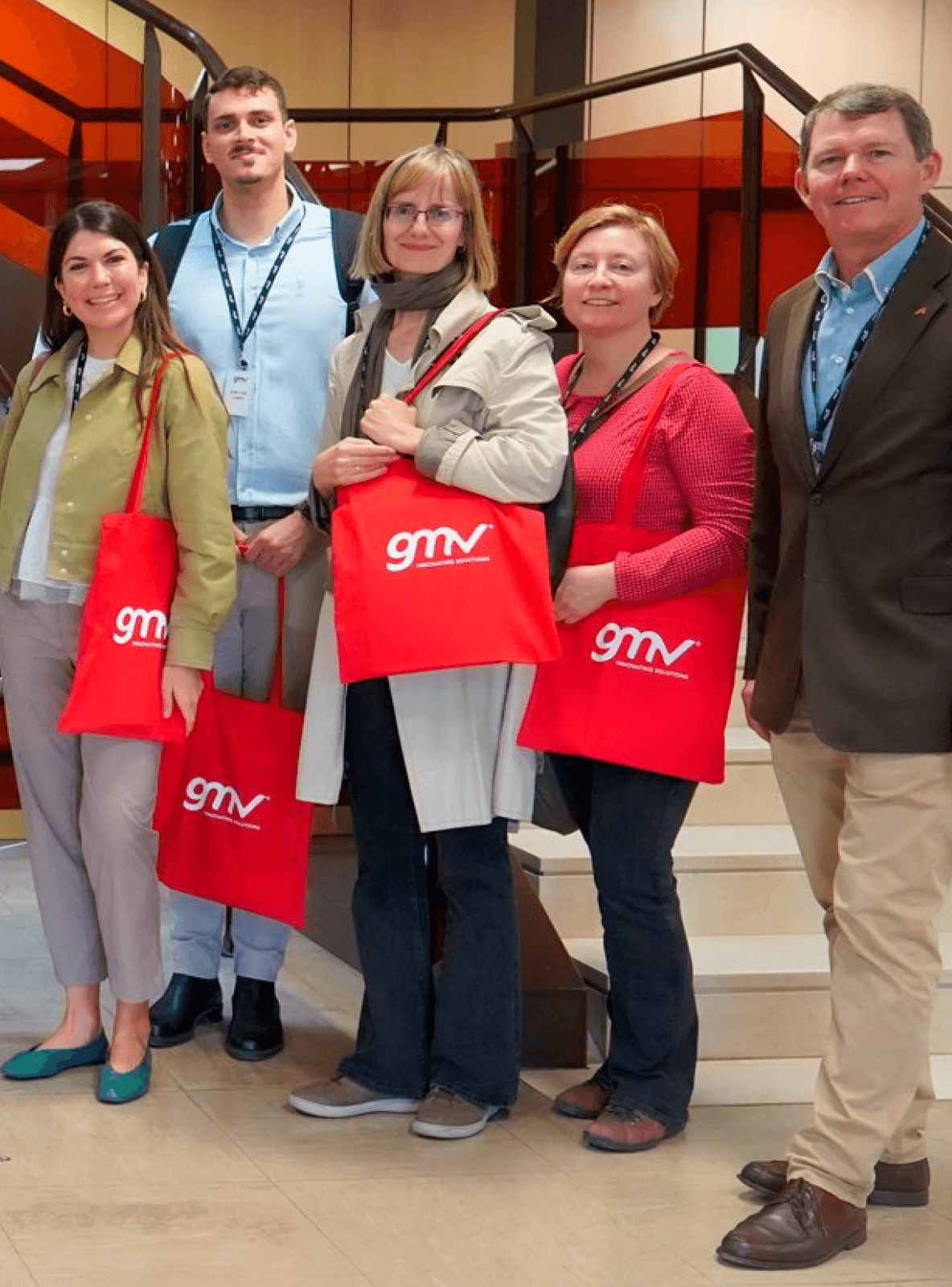 Image of five GMV employees holding branded tote bags.