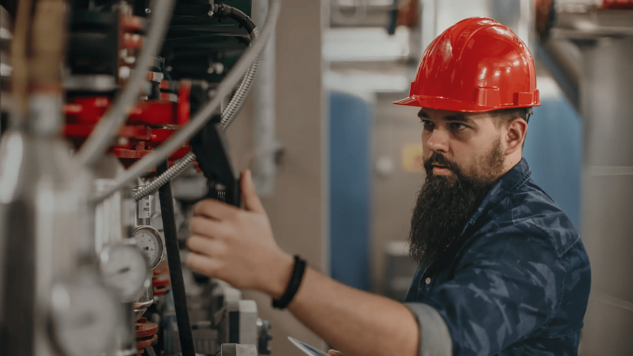 Image of a person wearing a hard hat and working in an industrial environment.