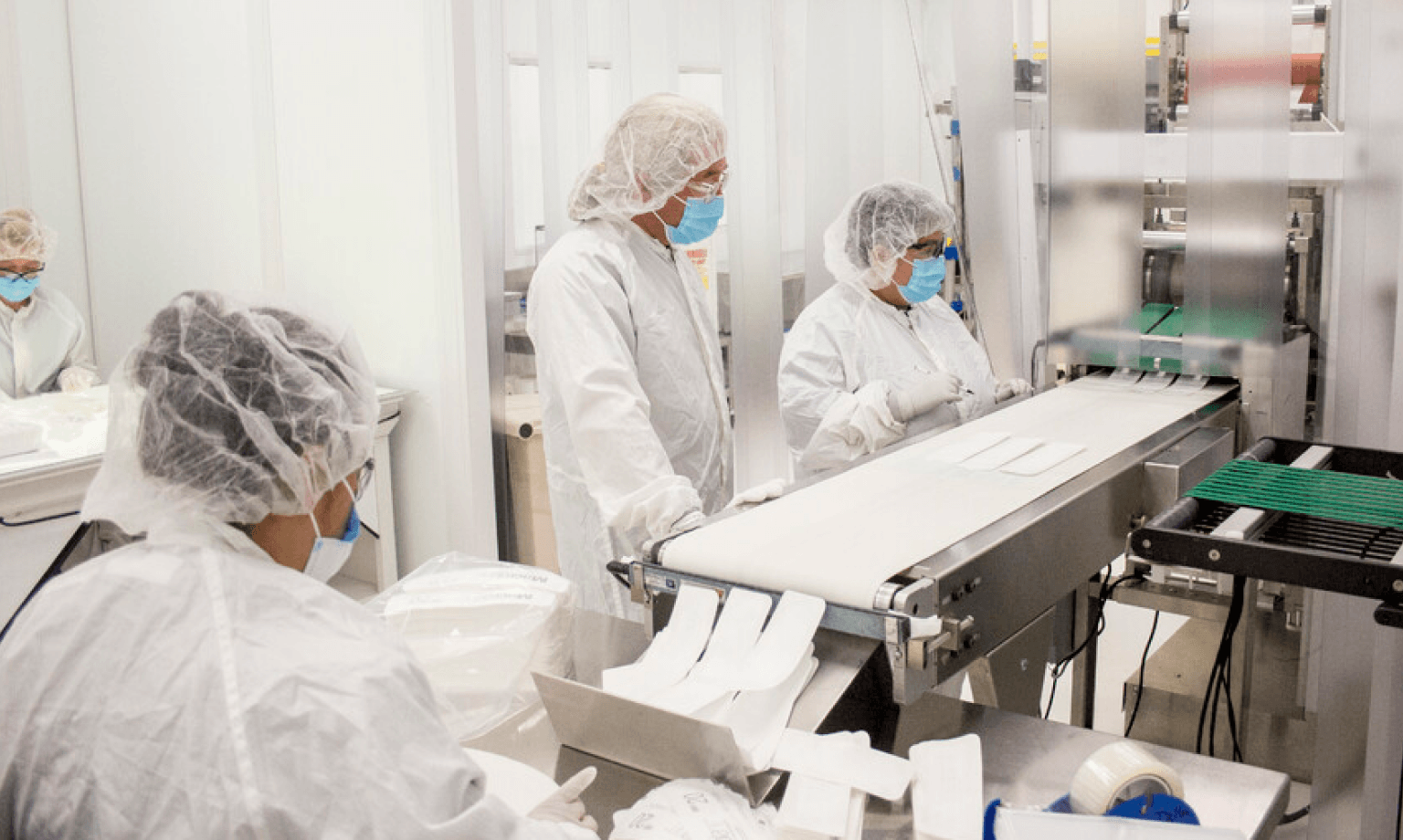 Employees in scrubs working with medical manufacturing machines.